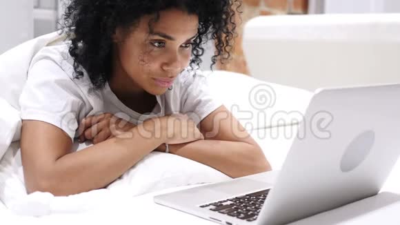 快乐的美国黑人妇女在床上工作手提电脑并对成功作出反应视频的预览图
