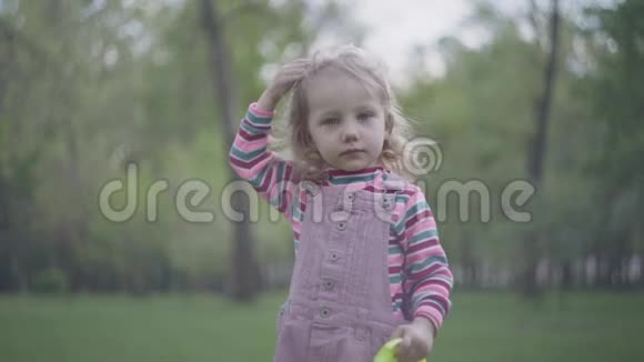 可爱的小女孩在她的皇冠上的前景绿色公园的背景皇冠太大了视频的预览图
