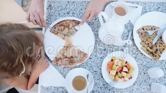 小女孩早餐吃煎饼妈妈把它们切成碎片视频的预览图