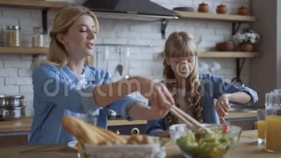 健康饮食妈妈给女儿放沙拉在盘子里4K视频的预览图