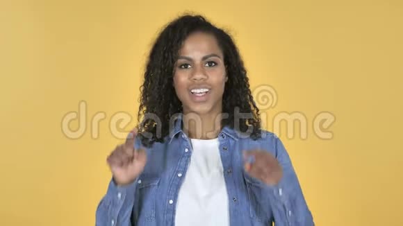 两只手分别在黄色背景下邀请顾客的非洲女孩视频的预览图