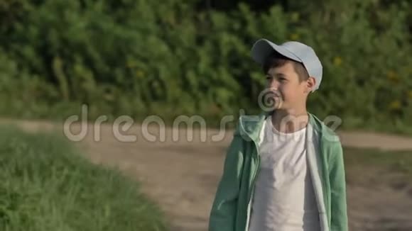戴着帽子的快乐男孩走在乡间小路上在户外微笑视频的预览图