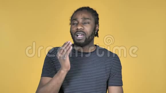 黄色背景下的非洲男子打哈欠和伸展身体视频的预览图