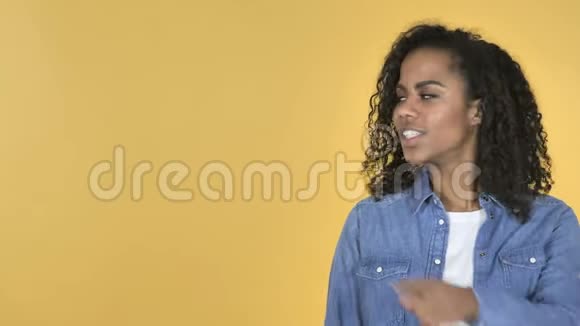 非洲女孩手指指向侧面黄色背景视频的预览图
