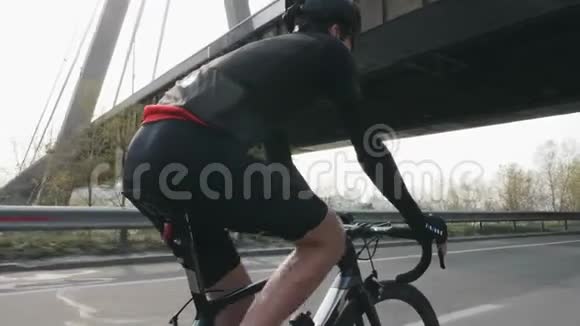 瘦瘦的骑自行车的人骑自行车在桥下后面跟着骑自行车的人在路上骑自行车慢动作视频的预览图