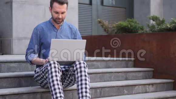 男人坐在楼梯上用笔记本电脑工作后就离开了视频的预览图