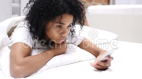躺在床上躺在肚子里打电话的美国黑人女人很放松视频的预览图