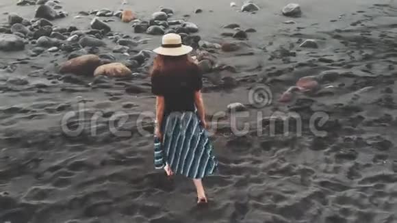 完美的空中镜头从特内里费岛一个年轻时尚的女孩戴着帽子走在一个黑色的视频的预览图