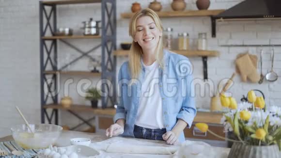 一个美丽的金发美女站在厨房的肖像女人看着观者微笑着4K视频的预览图