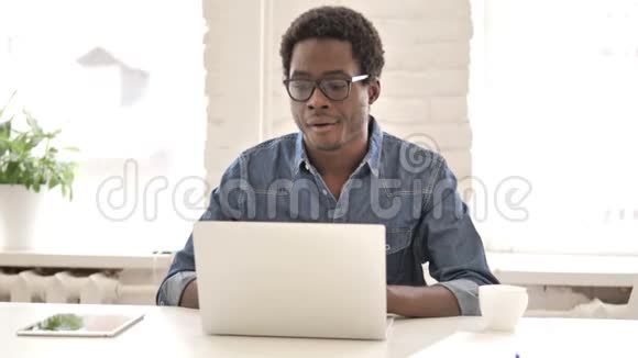 病态创意非洲男人咳嗽和在笔记本电脑上工作视频的预览图
