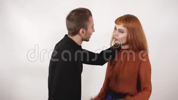 咄咄逼人的男人抓住女人的头发对女孩大喊大叫留着红色长发的女人试图保护自己视频的预览图