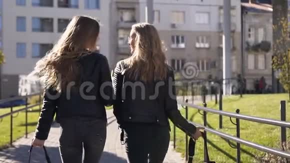 两位年轻时尚的女朋友留着长发背着时髦的背包在城里散步愉快地聊天视频的预览图