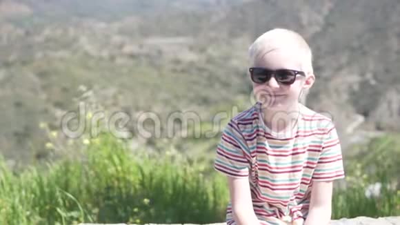 一个戴太阳镜的英俊的白化病男孩坐在对面视频的预览图