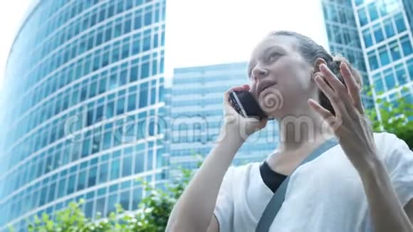 商务女性在电话中交谈用手在摩天大楼的背景上打手势视频的预览图