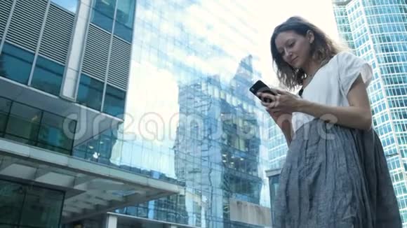 女人在街上的商业中心背景下使用智能手机视频的预览图