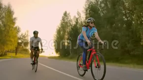 夏季在城市公园或林荫大道上骑自行车的年轻夫妇或朋友的正面景色人休闲视频的预览图
