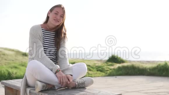 一位美女坐在靠近大海的桥上视频的预览图