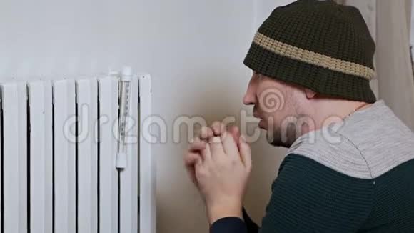 一个人在靠近电池的冬天测量房子的空气温度弱发热差穿着暖和的衣服视频的预览图
