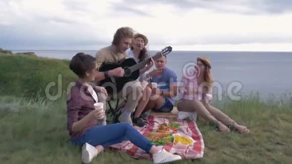 户外娱乐活动一群快乐的朋友在露天野餐时演奏乐器和唱歌视频的预览图