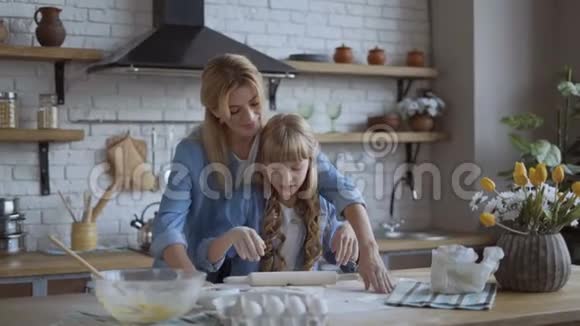 妈妈和女儿用一个木制的擀面杖擀出比萨饼面团幸福家庭的概念4K视频的预览图