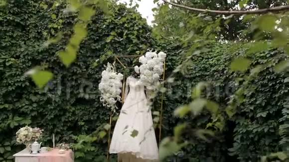 婚纱挂在华丽的婚礼拱门上上面覆盖着鲜花视频的预览图