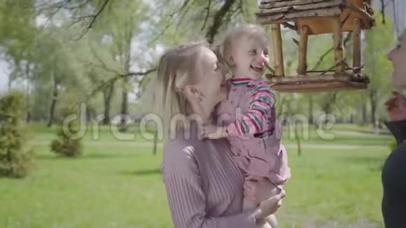 年轻的母亲和女儿一起在公园里度过时光女人抬起她的小女孩这样她就能看到鸟了视频的预览图