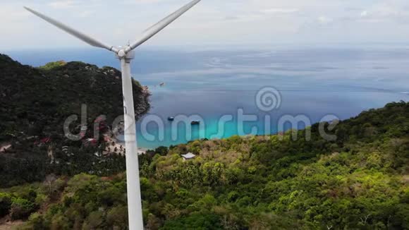热带岛屿的风力涡轮机白色风力涡轮机位于科陶的潜水员度假胜地对抗蓝色的海洋和多云的天空视频的预览图