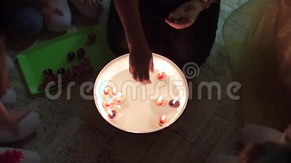 把蜡烛放在白色盘子里的水上的手的特写视频的预览图