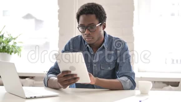 非洲男子在使用平板电脑时庆祝成功视频的预览图