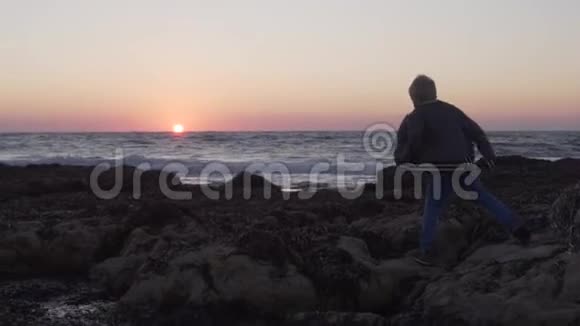 一个小男孩走在岩石海岸上相遇视频的预览图