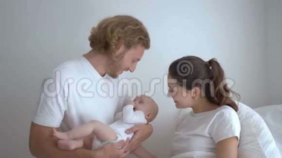 微笑着年轻的父母女人和男人抱着小婴儿在家享受视频的预览图