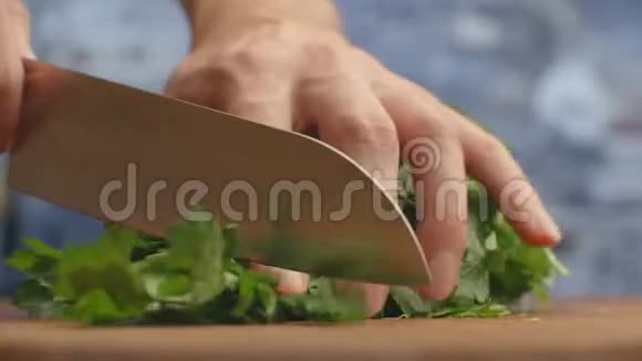 在厨房的一块木板上用刀子把切好的欧芹做成特写视频的预览图
