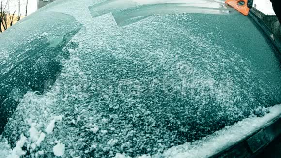 司机用刮刀缓慢地清理汽车挡风玻璃上的冰雪视频的预览图