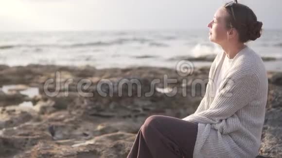 年轻时尚的女人坐在岩石海岸上视频的预览图