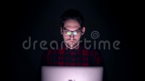 黑暗中监视器后面一个人的肖像男人看电影时脸上情绪视频的预览图