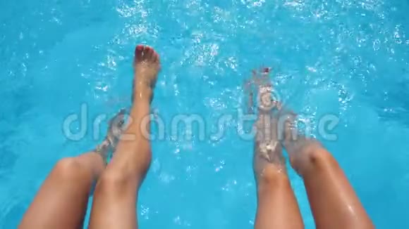 酒店泳池中女性双腿溅出晶莹剔透的水花两个朋友坐在盆边视频的预览图