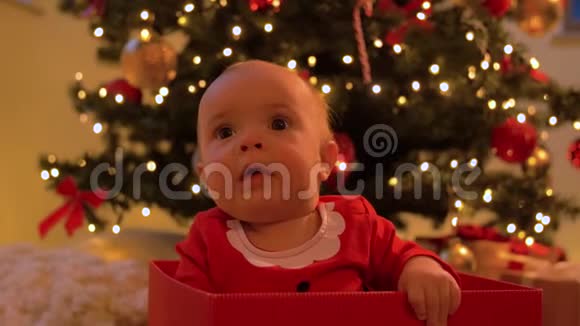 小女孩坐在圣诞树上的礼盒里视频的预览图