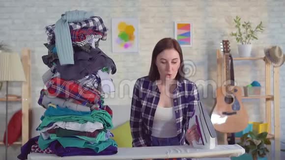 一堆衣服落在一个年轻的女家庭主妇身上视频的预览图