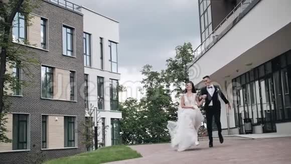 新娘和新郎正微笑着在城市里跑来跑去慢动作的美丽计划爱和家庭视频的预览图