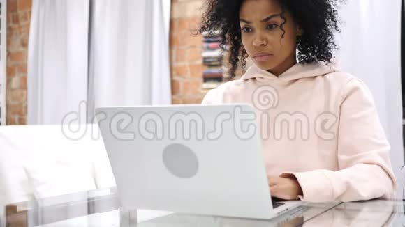 非裔美国妇女坐在沙发上因丢失而心烦意乱在笔记本电脑上工作视频的预览图