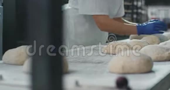 在一家商业烘焙行业专业的面包师辛勤工作为烘焙面包和面包制作面团视频的预览图