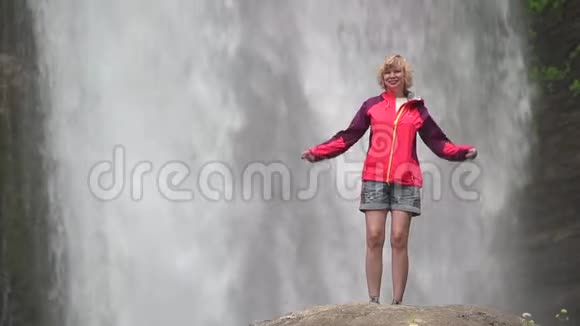 穿红色夹克衫在大瀑布附近跳舞的女人视频的预览图