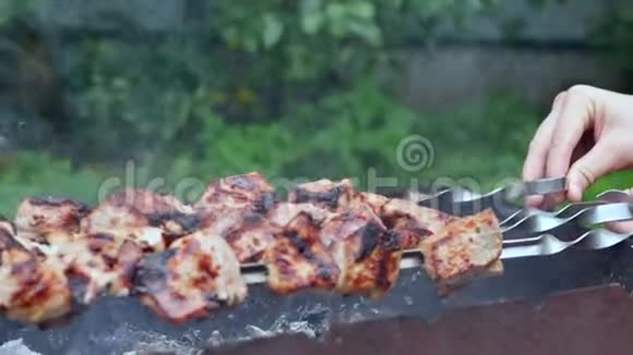 户外吸烟炭烤肉烧烤木炭烤架上的烤肉在烧烤活动上烹饪什什烤肉串双手合拢视频的预览图