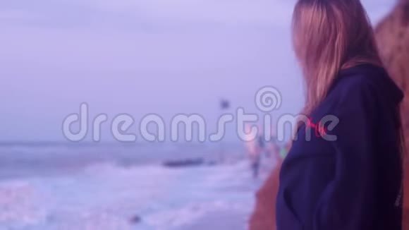 时髦的女孩看着蓝色冰冷的大海风浪和泡沫视频的预览图