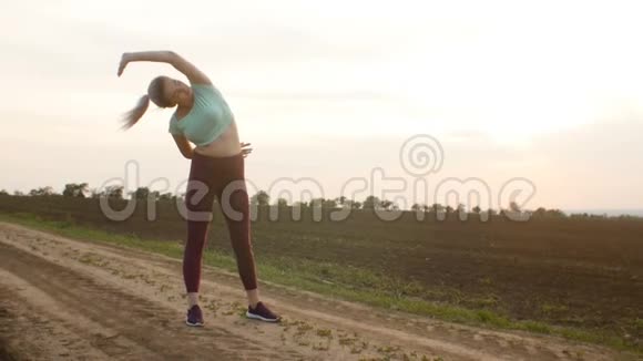 年轻女子扎着马尾在日落时分做运动锻炼女孩在户外健身生活方式的概念和他视频的预览图