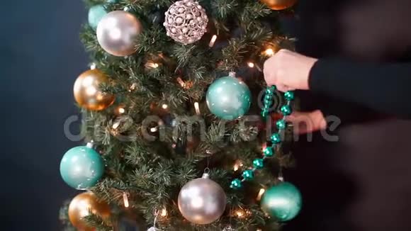 女人手的特写在圣诞树上放了一个花环视频的预览图
