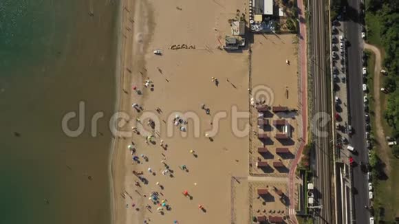顶部景观无人机在夏季海岸上方移动完美的公共金色沙滩配有椅子雨伞和清澈的水视频的预览图