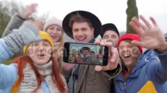 一群年轻的时髦朋友用智能手机相机自拍秋天森林的背景视频的预览图