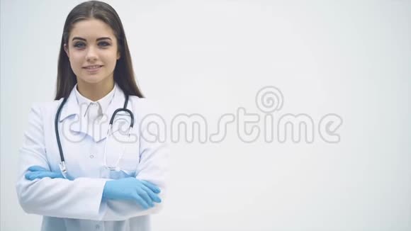 年轻的女实习生站在医疗制服上看着镜头微笑着双手交叉视频的预览图