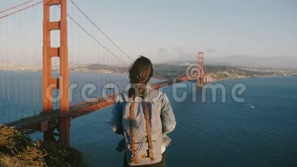 相机接近快乐的年轻当地妇女背包徒步旅行享受风景日落景观金门大桥美国视频的预览图